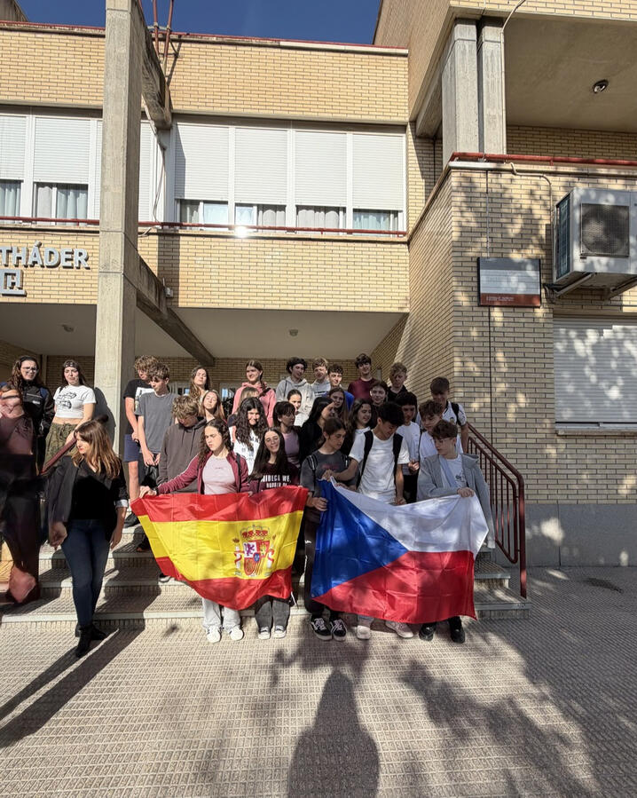 Čeští a španělští středoškoláci společně drží české a španělské vlajky před španělskou školou