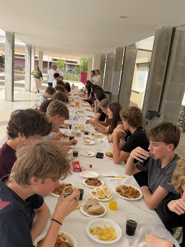 Studenti českých středních škol si užívají společný oběd s místními žáky během výměnného programu ve Španělsku. Na stole tradiční španělská paella, citróny a občerstvení. Čeští středoškoláci společně obědvají paellu během výměnného pobytu ve Španělsku